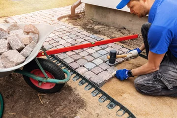 Zelfklevend Fotobehang werknemer legt granieten geplaveide weg rond het huis © ronstik