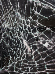 close up of shattered glass with white cracks on a black background