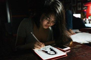 Professional asian woman tottooer designing a tattoo in studio