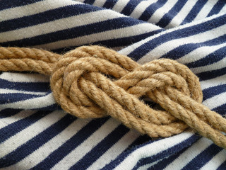 Double figure eight rope knot isolated on a striped blue white nautical shirt background. Flamand knot.