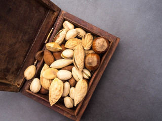 Assortment of nuts in a wooden box on a black background - healthy snack. Top view. Copy space