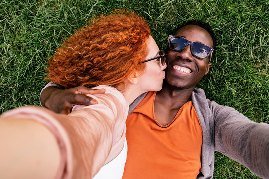 Embracing diverse couple chilling on grass