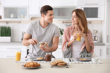 Happy couple having breakfast together in kitchen