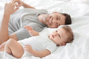 Handsome dad with his little son lying on bed at home