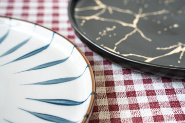black and white flat plate rested on coaster on red patterned napkin