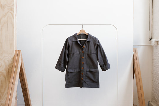 artist coat jacket hanging on clothing rack against white wall