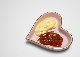 ketch up and honey mustard placed in heart shaped plate isolated in white background