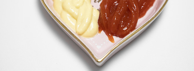 ketch up and honey mustard placed in heart shaped plate isolated in white background