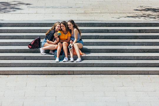 Three girls taking a selfie while sitting on the university stai
