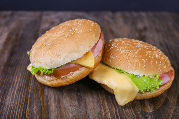 Hamburger with sausage and cheese with fresh lettuce on wooden background. Close up