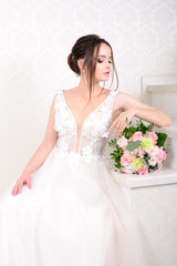 Slim beautiful woman wearing luxurious wedding dress over white studio background. Gorgeous bride holding flowers.