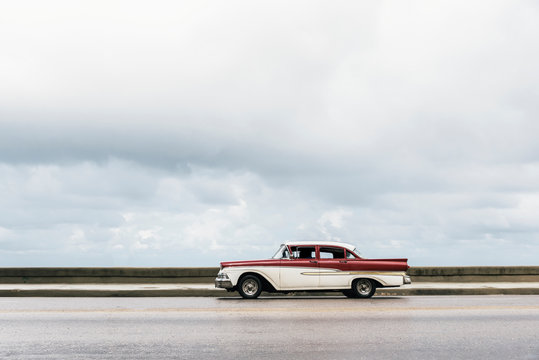 VIntage retro car with white roof riding on street of tropical c