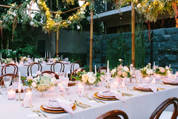 Outdoor, tropical wedding reception with hanging greenery garlands