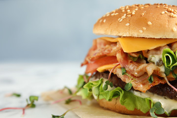 Tasty burger with bacon on table, closeup. Space for text