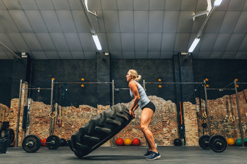 Muscular woman lifting car tire
