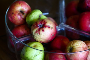 heap of organic red green ripe apples in glass bowl, small, gmo free,  no chemical treatments apples, in ambient light 