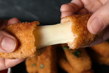 Woman holding broken cheese stick over table, top view