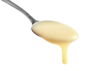 Spoon with condensed milk on white background, closeup. Dairy product
