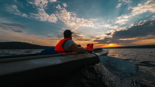 Father and a son go kayaking in the sunset