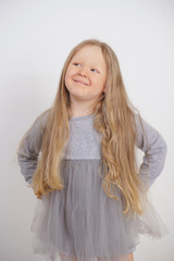 cute caucasian baby girl with long blond hair stands on white background in Studio