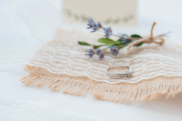 Close up photo of wedding boutonniere and ring on tablecloth