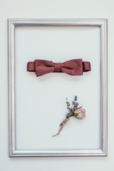 Closeup of elegant stylish brown male accessories isolated on white background in wooden frame. Top view of bow-tie