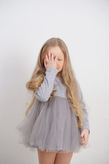 little girl child standing with a hand in the face with facepalm symbol on white background in Studio