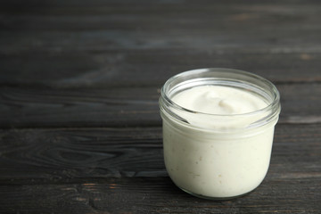Jar of garlic sauce on wooden background. Space for text