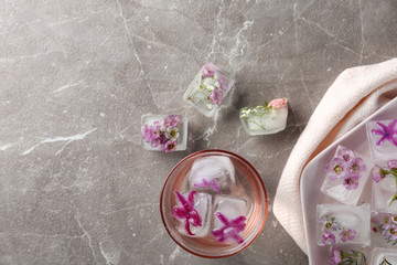 Flat lay composition with floral ice cubes on table. Space for text