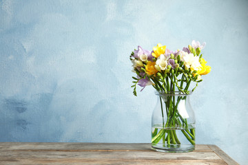 Bouquet of fresh freesia flowers in vase on table. Space for text