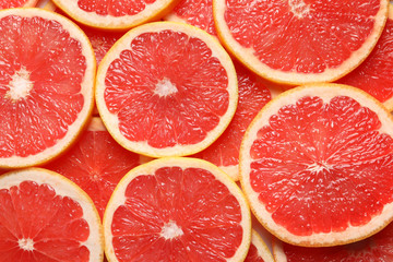 Juicy grapefruit slices as background, top view. Citrus fruit