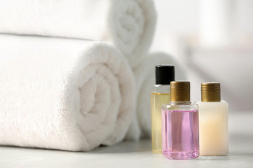 Mini bottles with cosmetic products and towels on table. Hotel amenities