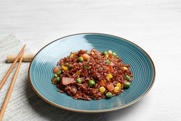 Plate of boiled brown rice with vegetables served on table
