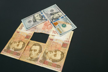 House of bills. The house has a roof of dollar bills. The bills are on a dark table.