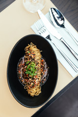 Top view of Capellini Cold Pasta with Hikiji Seaweed,  Chilled Lobster and Truffle Essence, Served in black bowl.