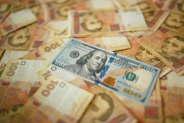 The American dollar is strewn with Ukrainian hryvnia. Dollar among hryvnia notes. Money background