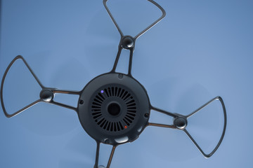 Quadcopter drone hovering in a blue sky
