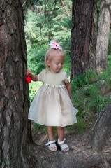 Little beautiful girl playing in nature in the forest. Standing under a tree, in the hands of a heart