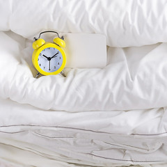 alarm clock and blankets. alarm clock sleep in white linen bed. Morning time background concept...