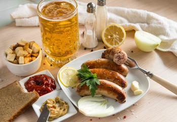 fried pork sausages with greens , onions, spices on a plate, sausages with ketchup, mustard, sausage on a fork, garlic , a mug of light beer, crackers,