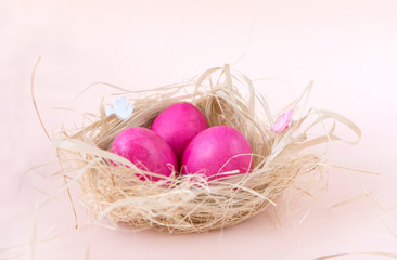 Naklejka na ściany i meble pink Easter painted chicken eggs in the nest on beige background
