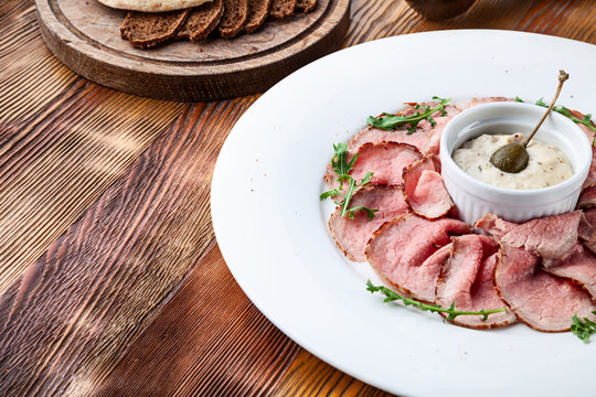 Close up view on traditional italian cuisine Vitello tonnato. A dish with pickled veal tuna cream sauce and bread on wooden background. Copy space for design, text. Snack before lunch. Close up food