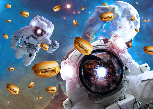 Astronauts in outer space with cheseburgers on the  pillar of creation and the Moon on the background. Elements of this image furnished by NASA