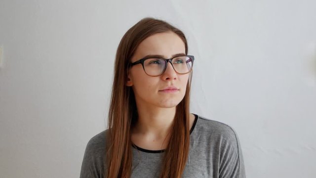 Sad thoughtful young beautiful female istanding in hesitation on white background