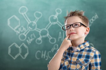 Cute little schoolgirl in glasses on blackboard background