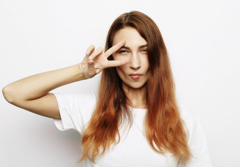 Fototapeta premium Portrait of gorgeous woman looking at camera with smile and showing peace sign with fingers
