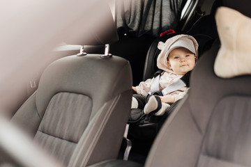 A one year old baby in a car sits in his special car seat and enjoys the upcoming trip.