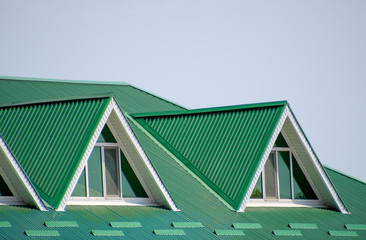 The house with plastic windows and a green roof of corrugated sheet. Green roof of corrugated metal profile and plastic windows.