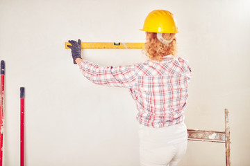 Working woman plastering / painting walls inside the house.