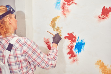 Working woman plastering / painting walls inside the house.